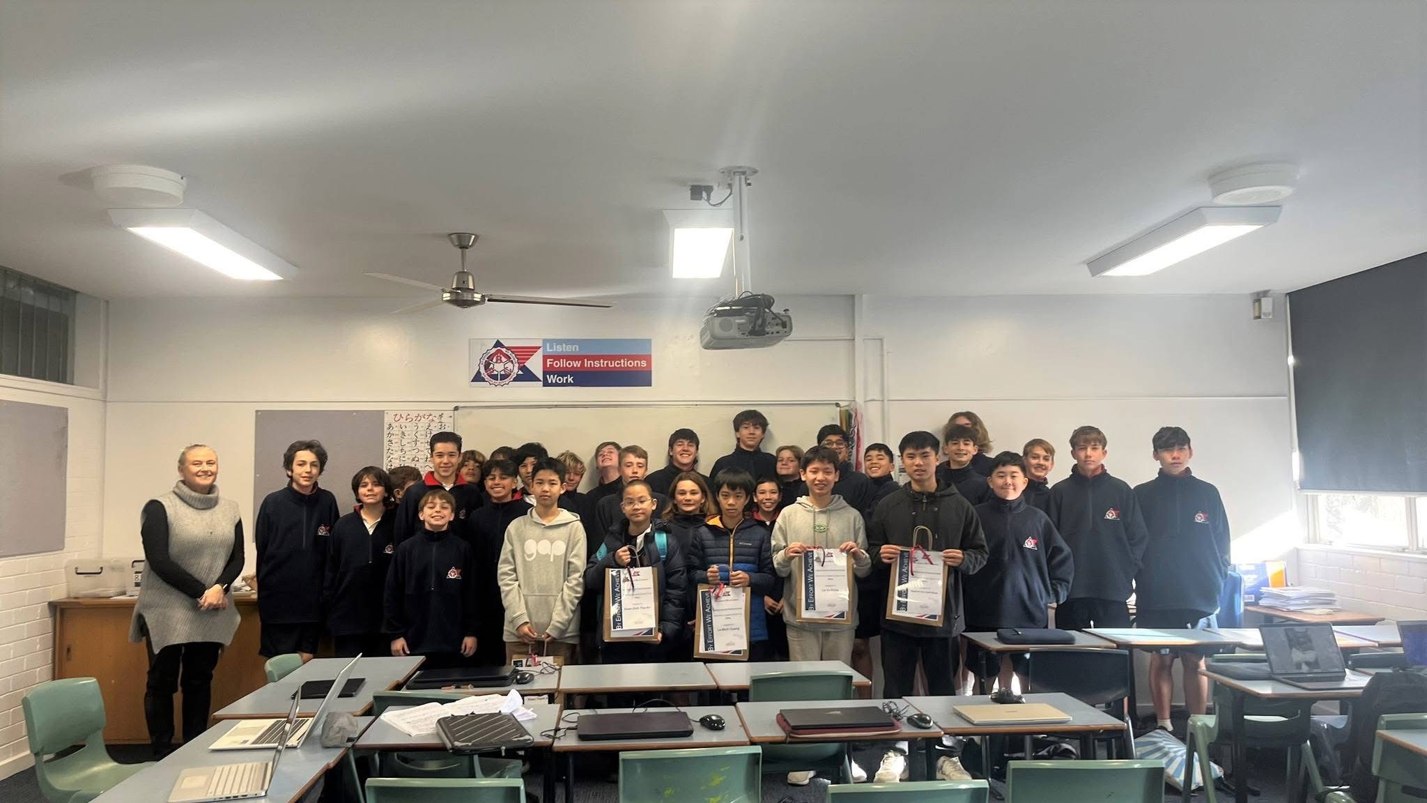 Students in a classroom during a study tour, holding certificates of achievement
